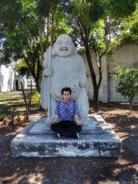 Man sitting on statue against trees