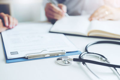 Close-up of documents and stethoscope on desk in hospital