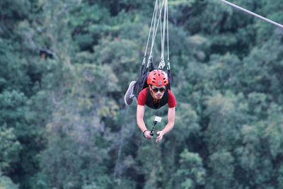 Full length of man ziplining on rope against trees