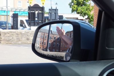 Reflection of man on side-view mirror of car