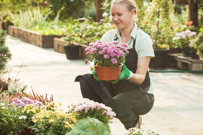 Beautiful young woman sitting on flower pot