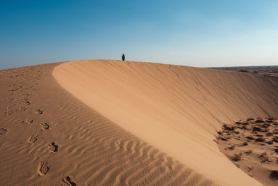 A tourist walking on a beautiful sand dune at north horr sand dunes in marsabit county, kenya