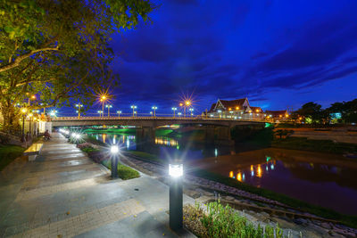 Illuminated bridge over river against sky at night