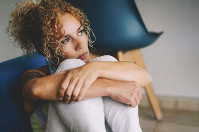 Thoughtful woman looking away while sitting at home