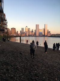 People on beach against buildings in city against clear sky