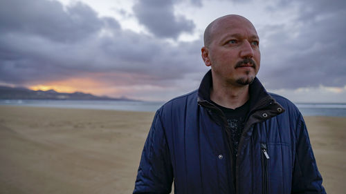 Portrait of mature man on beach against sky