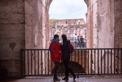 Rear view of people walking in front of historical building