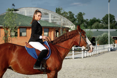 Portrait of young woman riding horse in city