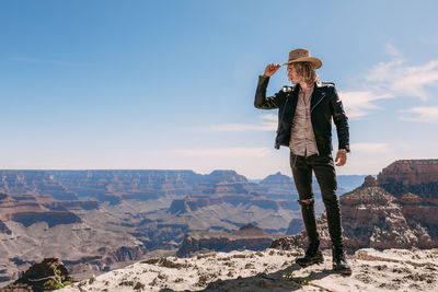 Man wearing hat standing on mountain against sky