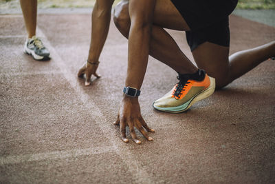 Low section of man kneeling at starting line on running track