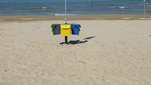 Garbage bins at beach on sunny day