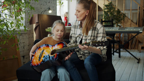 Mother teaching guitar to daughter