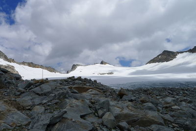 Snow covered mountains against cloudy sky