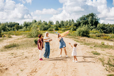 A charming little girl and her family are flying a kite. family, generation, time together