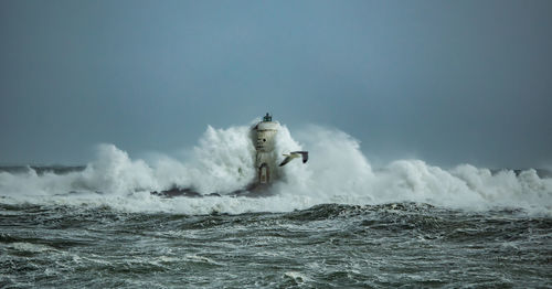 The lighthouse of the mangiabarche shrouded by the waves of a mistral wind storm
