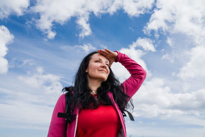 Young woman standing against sky