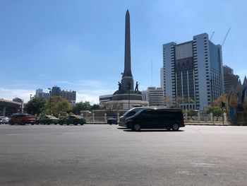 Cars on road by buildings against sky