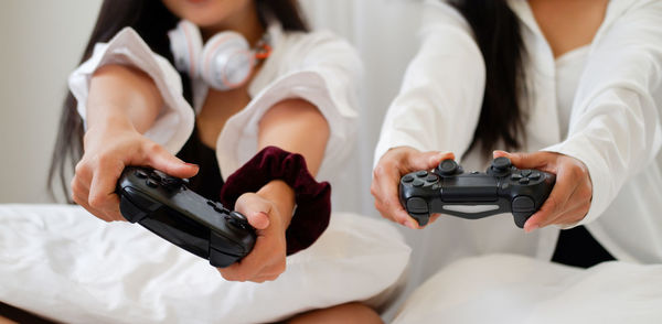 Midsection of friends playing video game at home