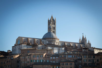 Buildings in city against clear blue sky