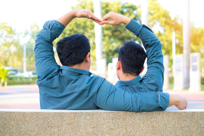 Rear view of homosexual couple sitting in city