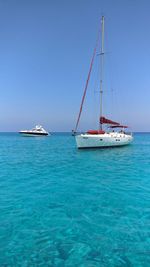 Sailboat and yacht in sea against sky