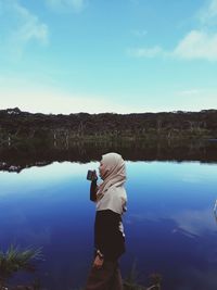 Man photographing lake against sky