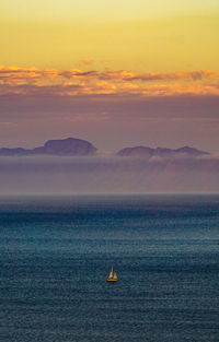 Sailboat sailing on sea against sky during sunset
