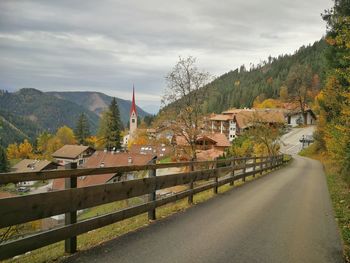 Road amidst trees in city against sky