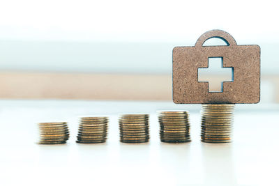 Close-up of stacked coins with first aid kit symbol on table