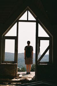 Rear view of woman standing against window