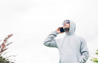 Low angle view of man using smart phone against sky