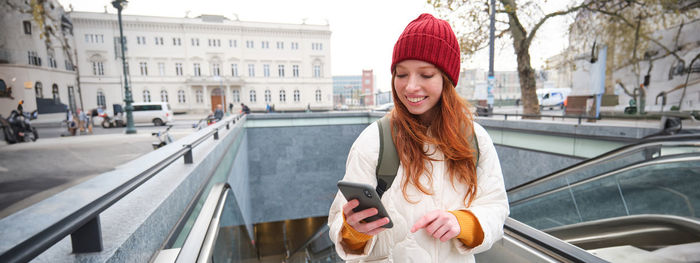 Portrait of smiling young woman standing in city