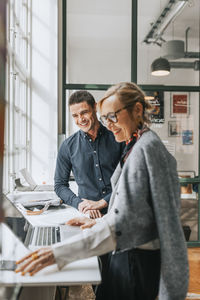 Happy male and female business people at desk in modern office