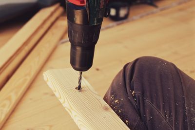 Cropped image of man using power tool on plank