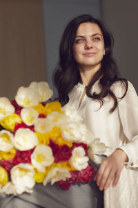 Portrait of young woman with flowers on table