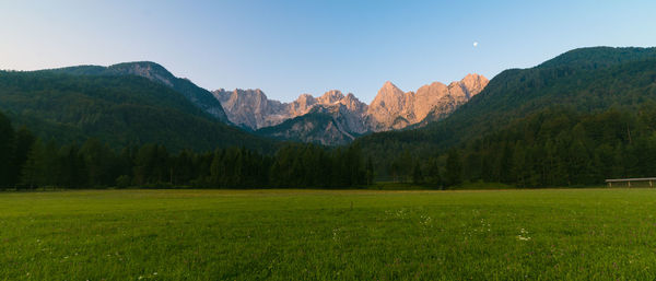 Scenic view of mountains by grassy field against sky