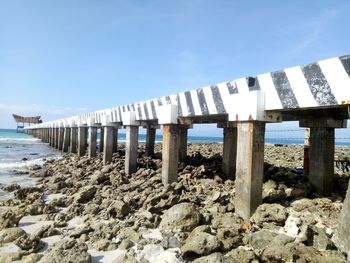 Wooden posts on beach against sky