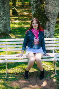 Smiling young woman sitting on bench in park