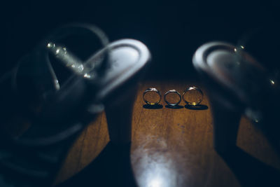 Close-up of wedding rings with high heels on hardwood floor in darkroom