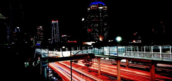 Illuminated bridge and buildings against sky at night