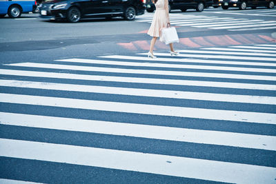 Low section of woman walking on zebra crossing