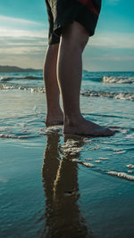 Low section of man standing on beach