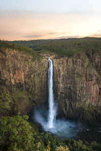 Scenic view of waterfall against sky during sunset