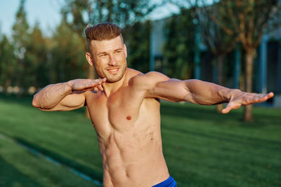 Portrait of shirtless man exercising in park