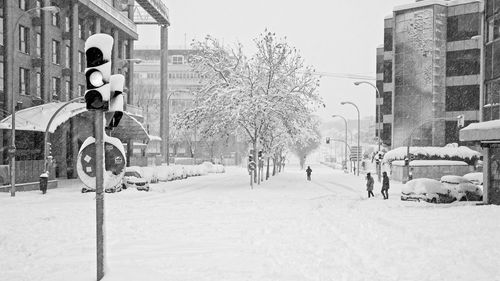 Snow covered street amidst buildings in city