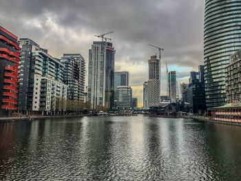 River by buildings in city against sky