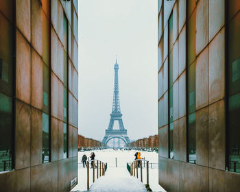 Eiffel tower seen amidst buildings against sky during winter