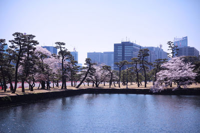 Bridge over river by buildings against clear sky