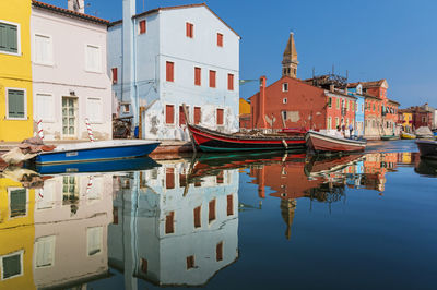 Sailboats moored on canal by buildings in city