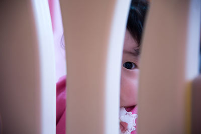 Portrait of cute girl looking through crib at home